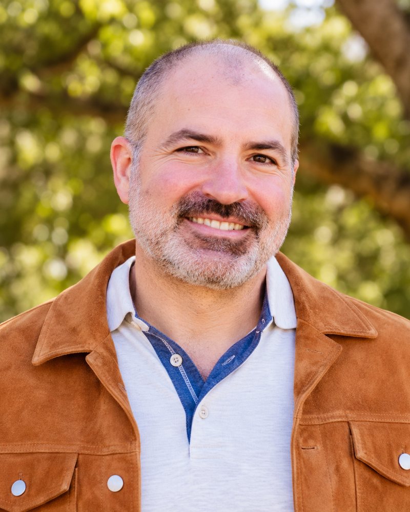 Michael Puente, smiling, in a tan suede jacket outdoors